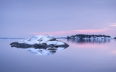 Pale purple and pink colors of a winter sunset in the Swedish archipelago outside Stockholm