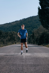 Male athlete running on an empty road in the woods while trying to get to the red finish line.