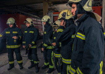 Firemen preparing for emergency service. Firefighters putting on gloves.