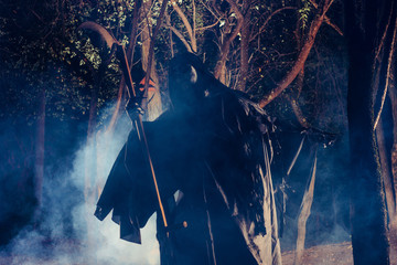 Naklejka premium Grim Reaper standing in the fog at night with his scythe.