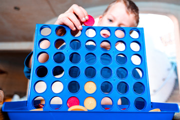Child playing a traditional strategy game to form 4 chips row.