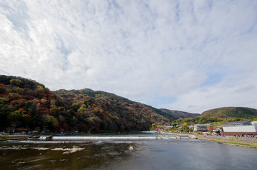 Fototapeta na wymiar Katsuragawa river with colourful forest mountain background in Arashiyama, Kyoto