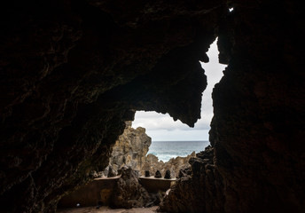 Fototapeta na wymiar Cave in volcanic rock in Porto Moniz, a tiny resort village in Madeira. Arrow or church like a keyhole in the cliff that shows the coastline and rough sea water. Dark frame around autumn day on ocean.