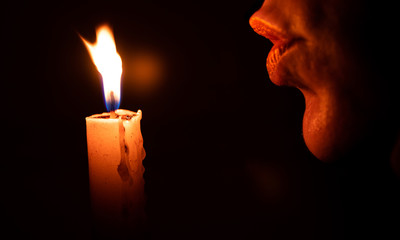 Woman blowing a candle with dark background