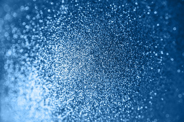 Blue background with glitter. Shining flare blurred bokeh texture. Trendy concept classic color, empty space for text.