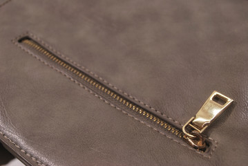 The zipper edge of the brown leather bag.