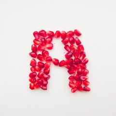 letter A folded from pomegranate berries on a white background top view