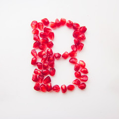 letter B folded from pomegranate berries on a white background top view