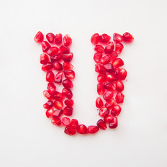 letter U folded from pomegranate berries on a white background top view