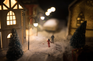 New Year miniature house in the snow at night with fir tree. Holiday concept. Selective focus