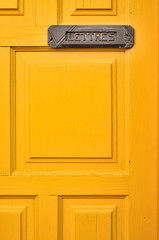 Orange door with a letter box and a French word LETTRES (English: MAIL).