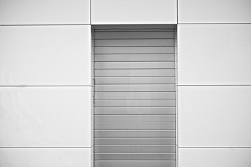 Silver door closed with aluminum shutters in a gray metalic wall, a simple minimal architecture detail.