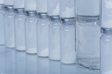 Glass medical ampoule vial for injection. Medicine is dry white drug penicillin powder or liquid with of aqueous solution in ampulla. Close up. Bottles ampule with aluminum cap on backgrounds gray.