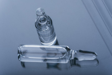 Glass medical ampoule vial for injection. Medicine is dry white drug penicillin powder or liquid with of aqueous solution in ampulla. Close up. Bottles ampule with aluminum cap on backgrounds gray.