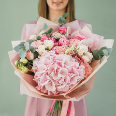 Colorful bouquet of different fresh flowers in the hands of a florist woman. Rustic flower background. Craft bouquet of flowers.