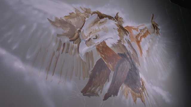 Artist designer draws an eagle on the wall. Craftsman decorator paints a picture with acrylic oil color. Painter painter dressed in a paint coat. Indoor. Dark magic cinematic look.