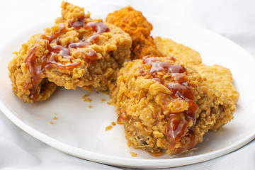 Crispy chicken fried breast in a white plate topped with ketchup sauce.
