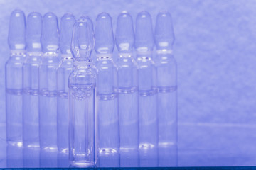 Glass medical ampoule vial for injection. Medicine is liquid sodium chloride with of aqueous solution in ampulla. Close up. Bottles ampule multicolor on background color and water. Human plasma.