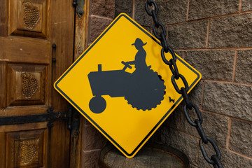 Tractor crossing warning road sign used as decor with Metal chain on Traditional barrel next to a wooden door, vineyard house entrance