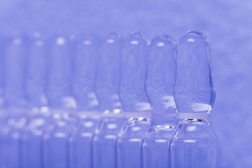 Glass medical ampoule vial for injection. Medicine is liquid sodium chloride with of aqueous solution in ampulla. Close up. Bottles ampule multicolor on background color and water. Human plasma.