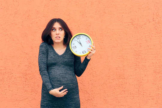 Worried Pregnant Woman Holding a Clock Awaiting her Baby