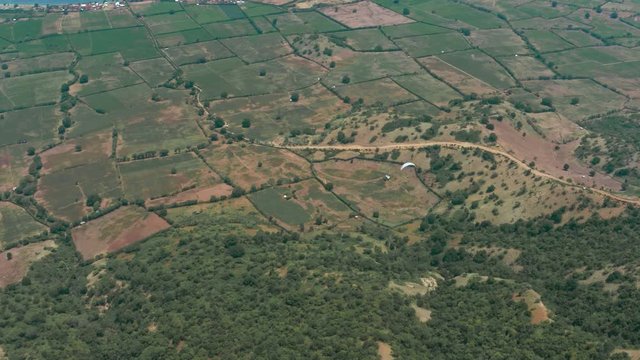 Amazing aerial video of flying paraglider on the background of wild nature. Paraplan drifting above the green tropical trees. Extreme sport. Hipster modern hobby concept. Paraplane flying in the sky.