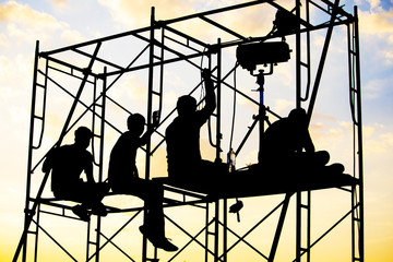 The staffs are on the crane at the outdoor concert construction with the sky in the evening or early morning , silhouette style.