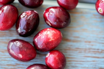 Macro view on group of bright glossy red cranberries on wooden surface