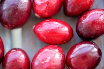 Macro view on group of bright glossy red cranberries on wooden surface