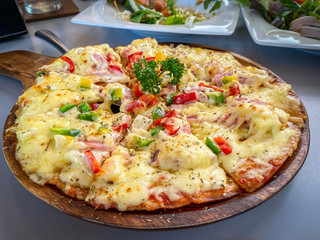 Sliced hawaiian pizza with ham and cheese on the table.