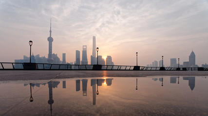 Landscape of Shanghai bund in the morning before sunrise with reflections in water.	