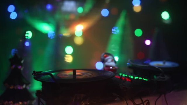Christmas and New Year club concept. Dj mixer with headphones on snow. Santa Claus is mixing on turntable. Creative miniature artwork decoration on snow.