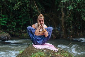 Yoga practice and meditation in nature. Man practicing near river
