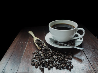 white cup of coffee with wooden spoon full of coffee beans on the table