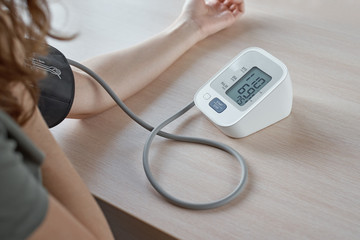 Woman measuring blood pressure with an electric digital tonometer.  Healthcare and medicine concept - obrazy, fototapety, plakaty