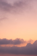 Cloudy orange evening sky and moon