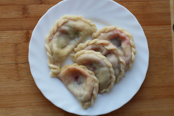 dumplings with cherries on white plate on wooden table