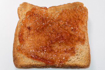 Top view strawberry jam on one piece of whole wheat toast. Own slice of brown breakfast bread with jam.