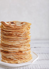 Cooking pancakes. Shrovetide (Maslenitsa) - blini stack on a blue plate on a wooden table.