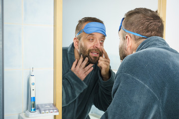 Sleepy man looking at mirror