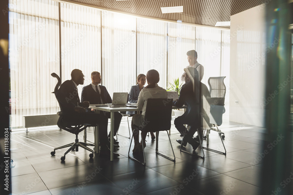 Wall mural silhouettes of people sitting at the table. a team of young businessmen working and communicating to