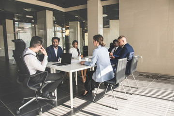 Silhouettes of people sitting at the table. A team of young businessmen working and communicating together in an office. Corporate businessteam and manager in a meeting