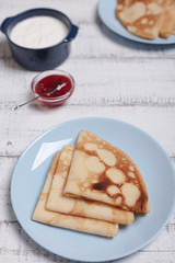 Cooking pancakes. Shrovetide (Maslenitsa) - blini stack on a blue plate on a wooden table.