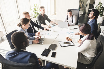 A team of young businessmen working and communicating together in an office. Corporate businessteam and manager in a meeting