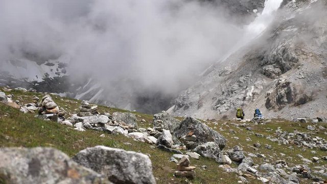 Two hikers on a cloudy mountain ridge