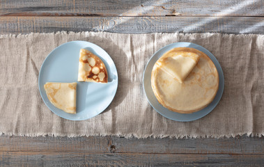 Cooking pancakes. Shrovetide (Maslenitsa) - blini stack on a blue plate on a wooden table.