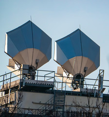 Satellite dish on the roof of the building against the blue sky.