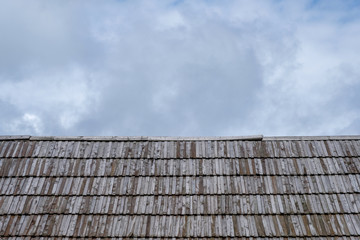 Fototapeta na wymiar Wooden roof with cloudy sky in background.
