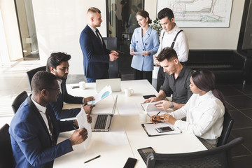 A team of young businessmen working and communicating together in an office. Corporate businessteam and manager in a meeting.