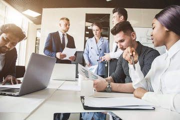 A team of young businessmen working and communicating together in an office. Corporate businessteam and manager in a meeting.